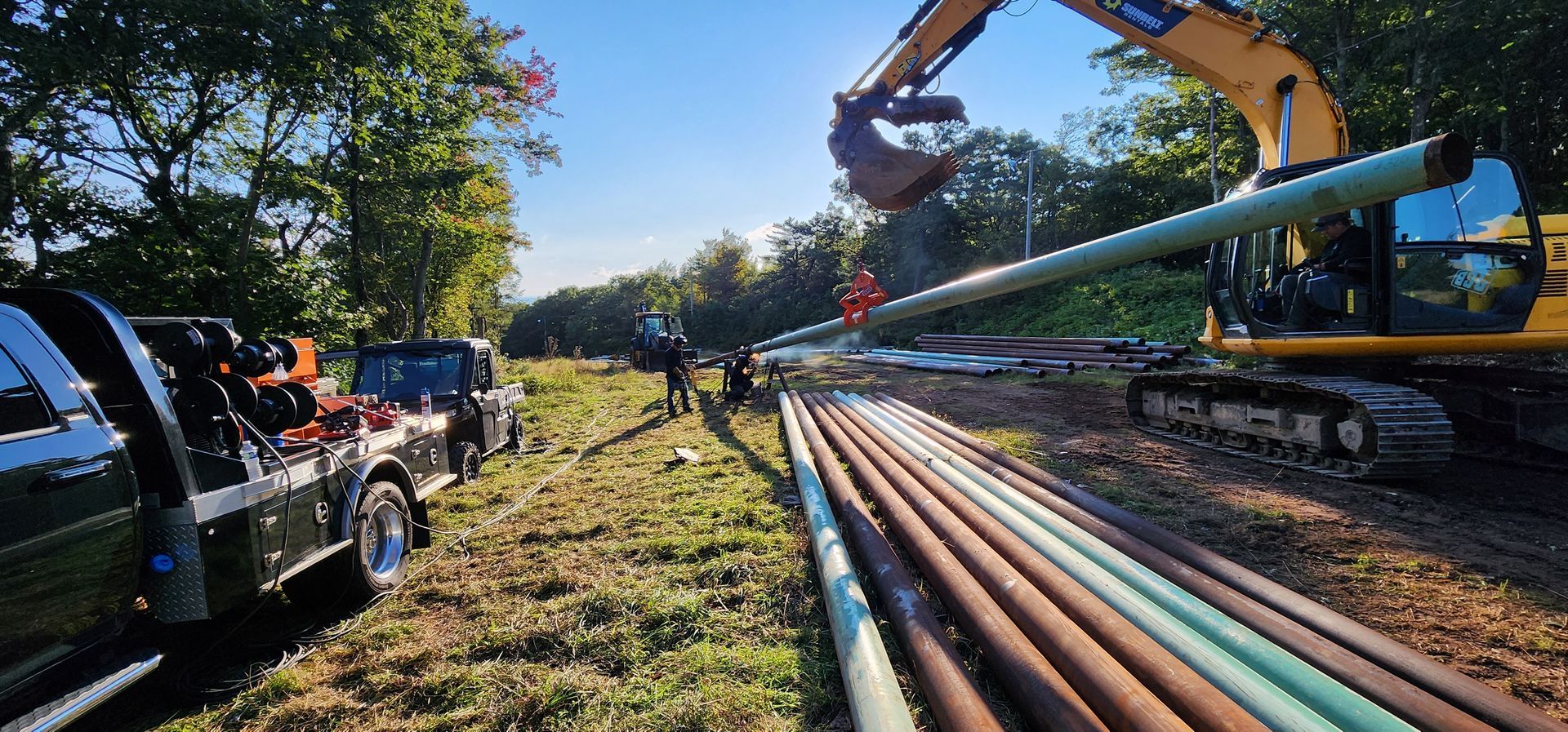A truck is parked in a field next to a large excavator.