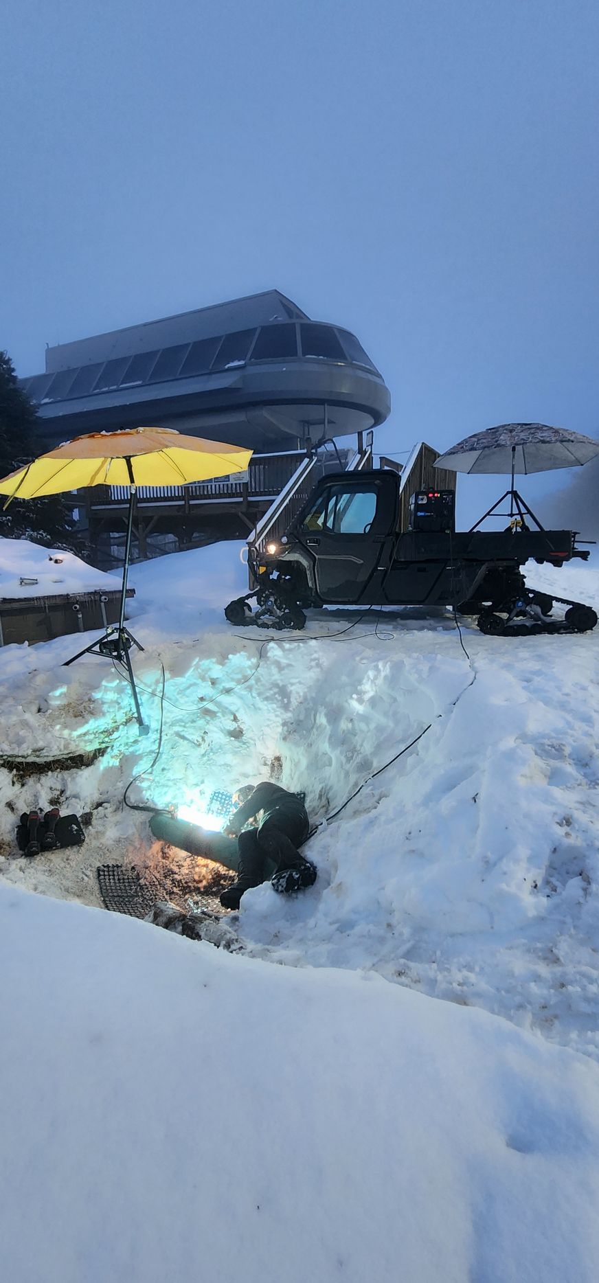 A snowmobile is parked in the snow in front of a ski lift.