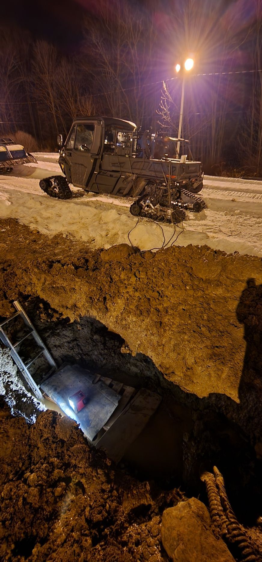 A military vehicle is sitting in a hole in the ground at night.