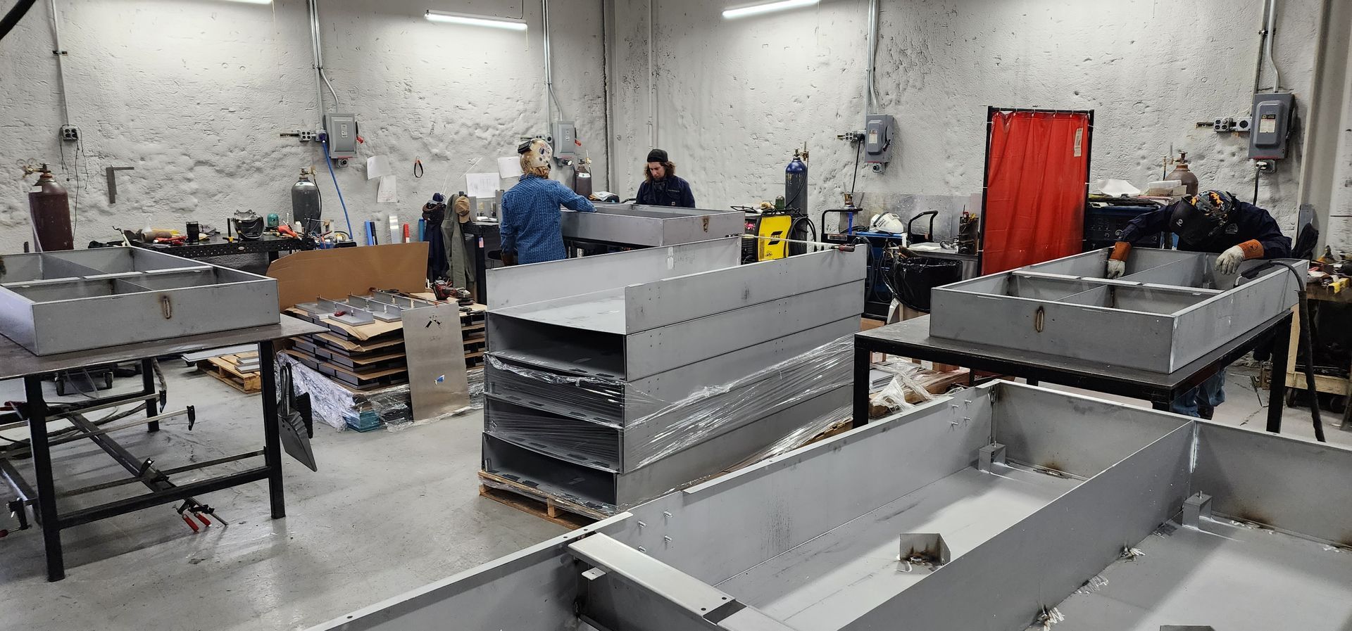 A factory filled with lots of metal pieces and people working on them.