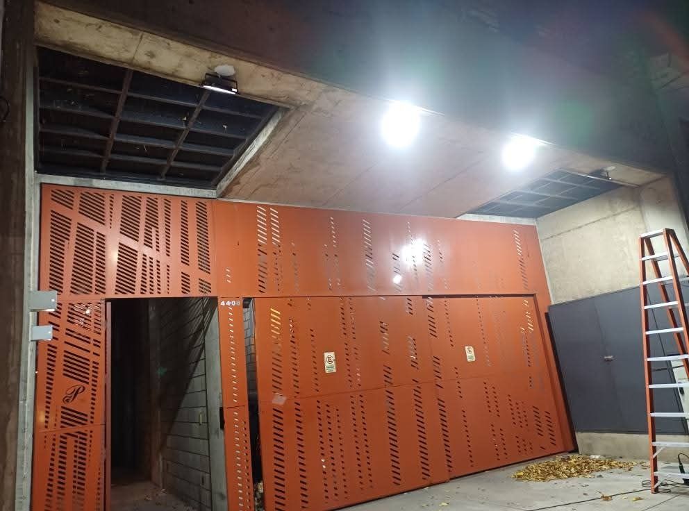 Paneles de pared de metal de color naranja en construcción; dos luces en el techo.