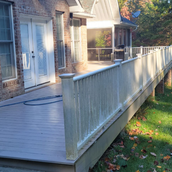 a large deck with a white railing is in front of a brick house .