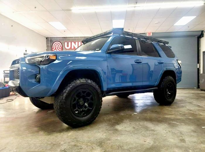 A blue toyota 4runner is parked in a garage.