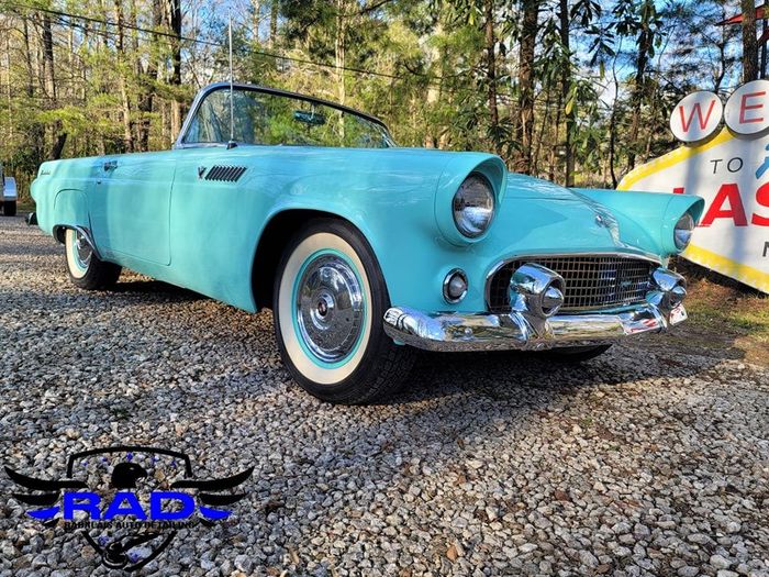 A thunderbird convertible is parked on gravel in front of a gas station.