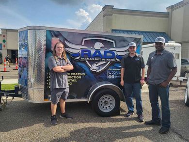 Three men are standing in front of a trailer that says rad.