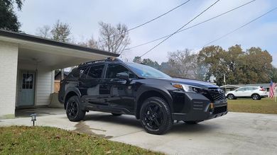 A black suv is parked in front of a house.