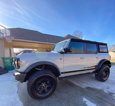 A white jeep is parked in front of a house.