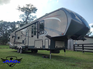 A large rv is parked in a grassy field.