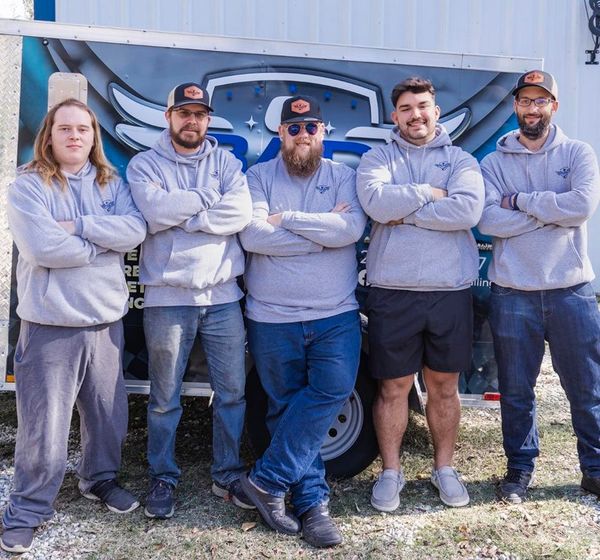 A group of men are posing for a picture in front of a truck.