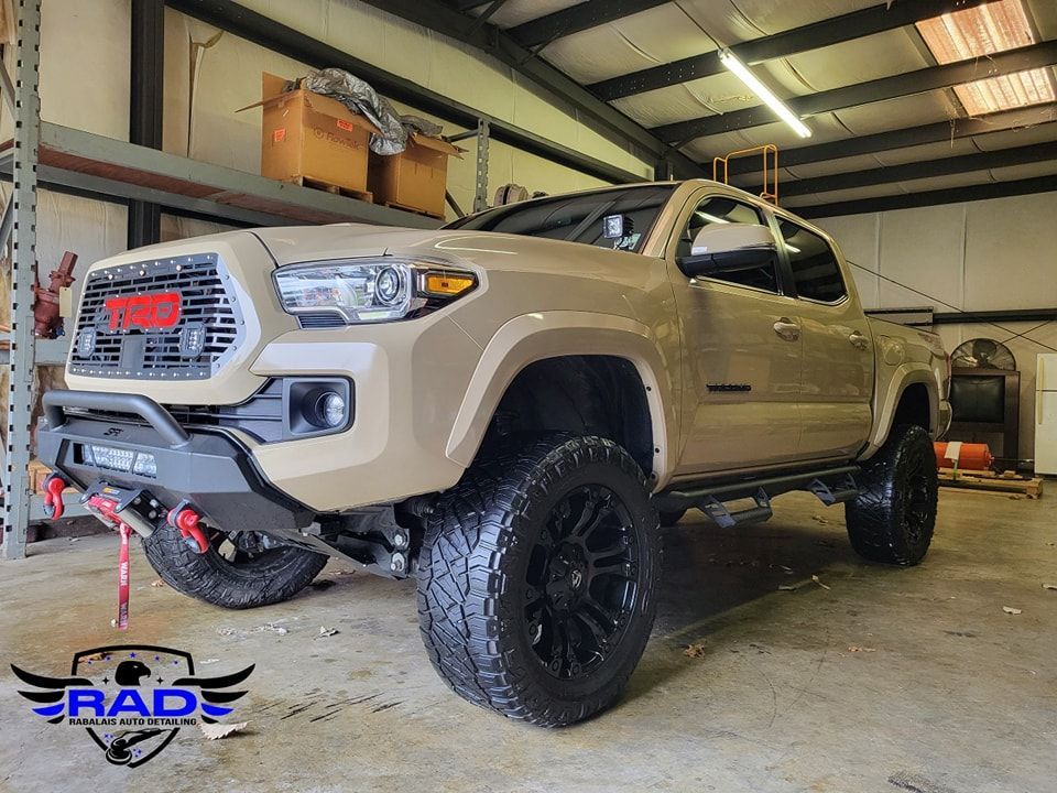 A tan toyota tacoma truck is parked in a garage.