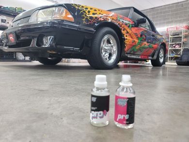 A car is parked in a garage next to two bottles of liquid.