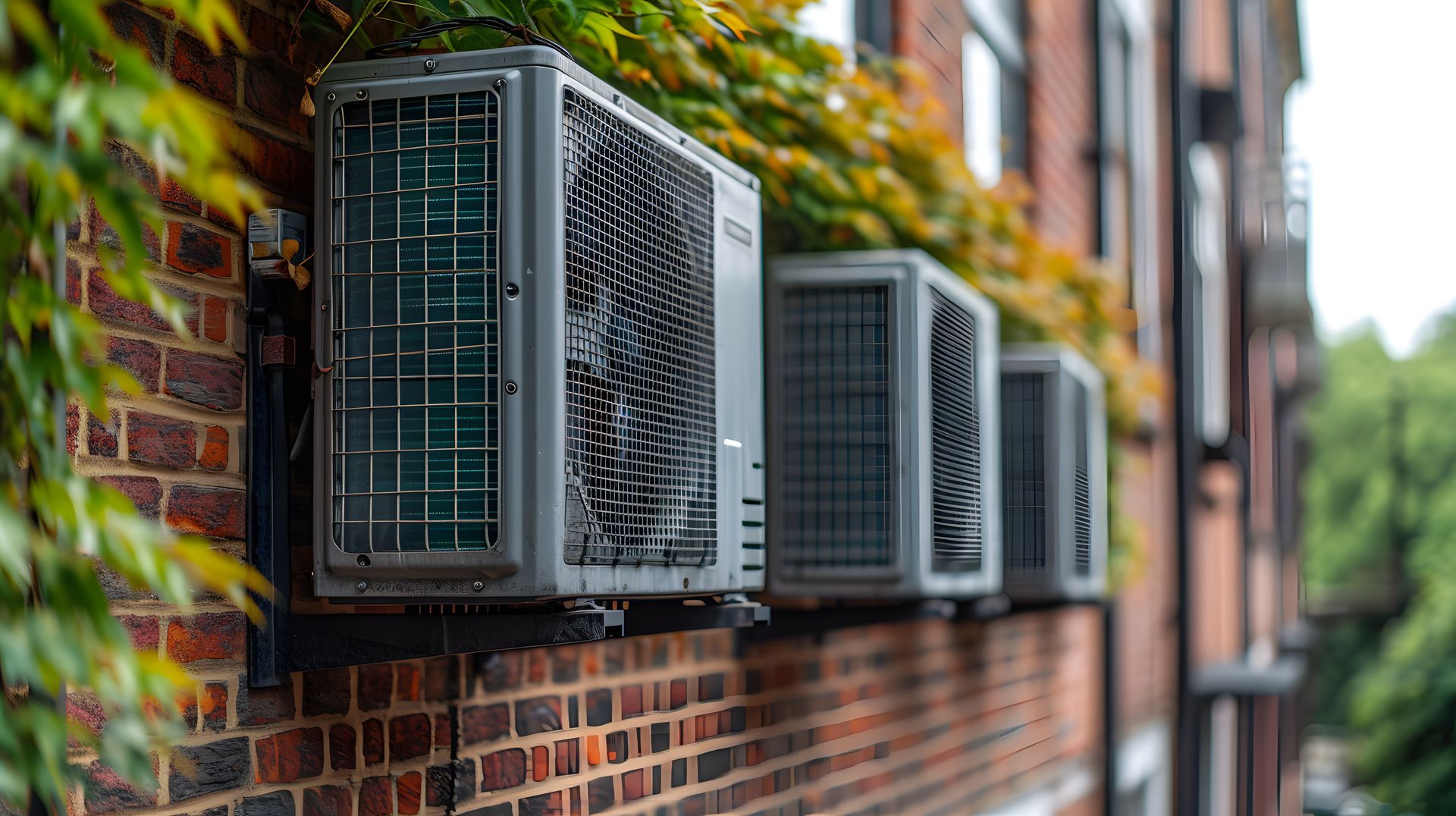A row of air conditioners mounted on the side of a brick building.
