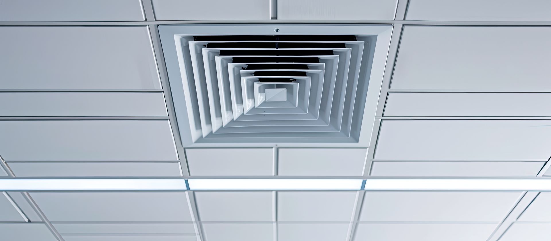 A square air vent is hanging from the ceiling of a room.