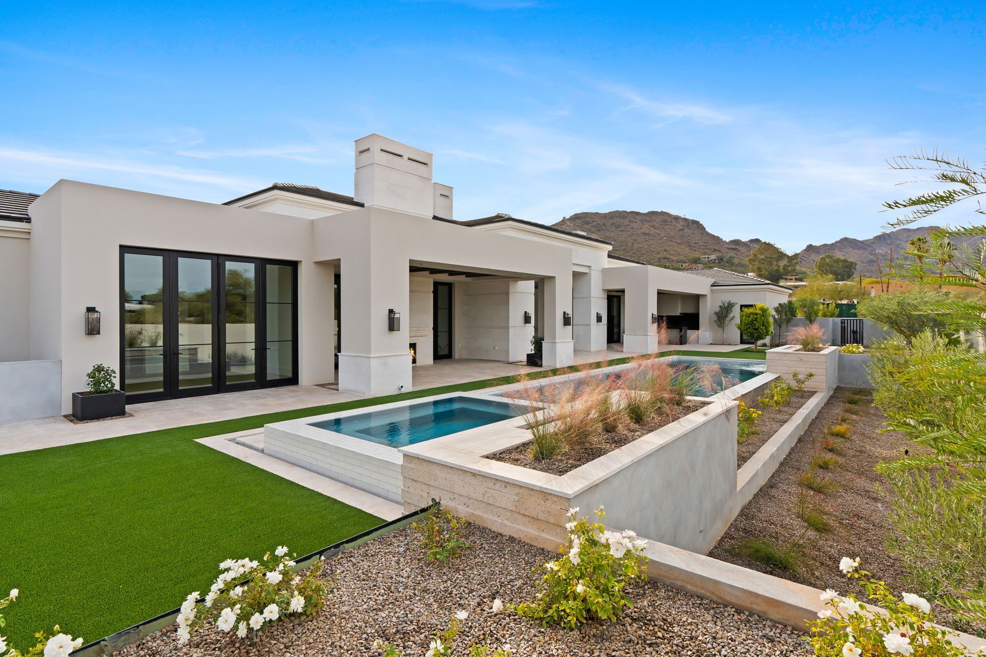 Luxury home with pool, green lawn, and mountain backdrop.