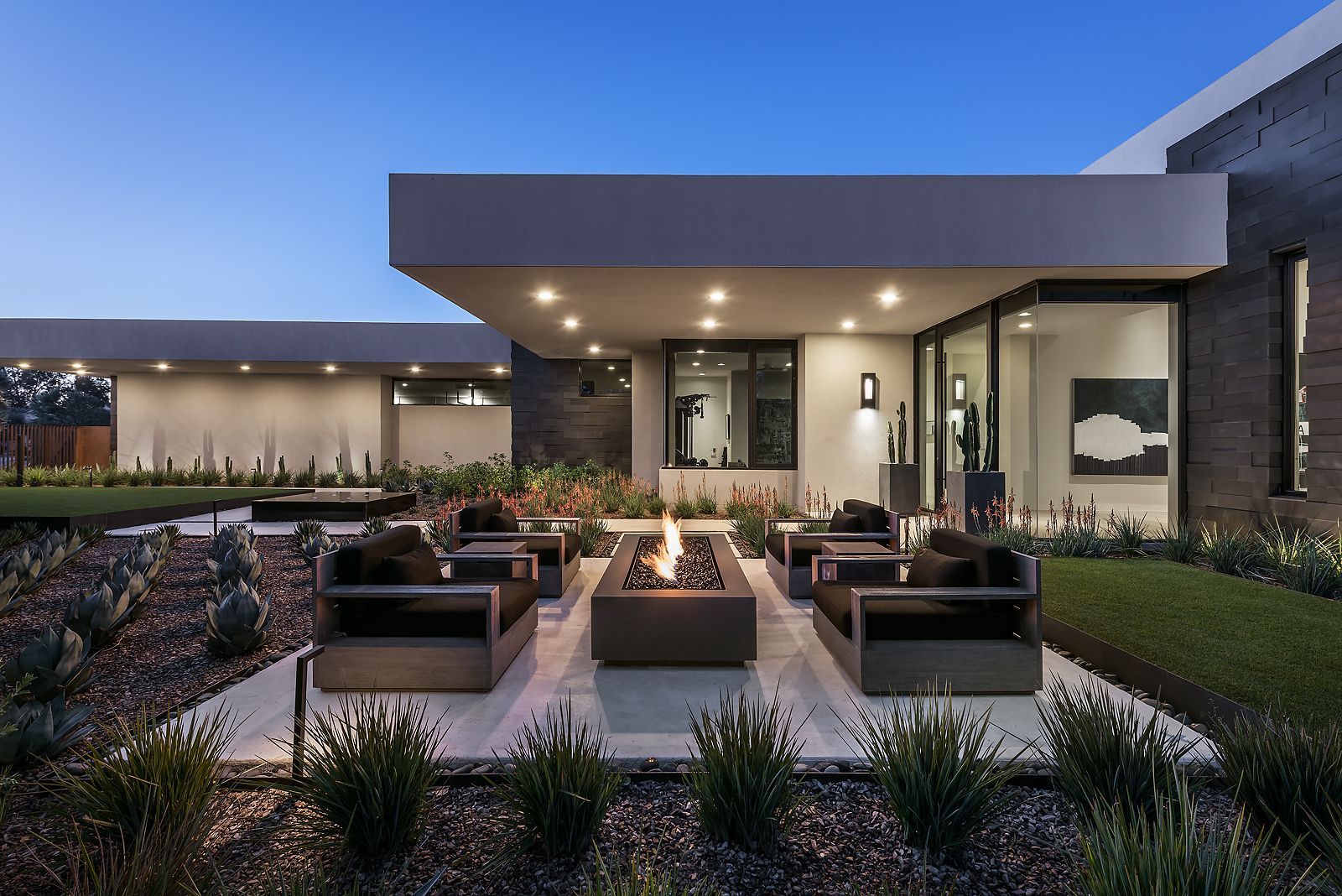 Outdoor seating area with fire pit, modern home exterior at dusk.