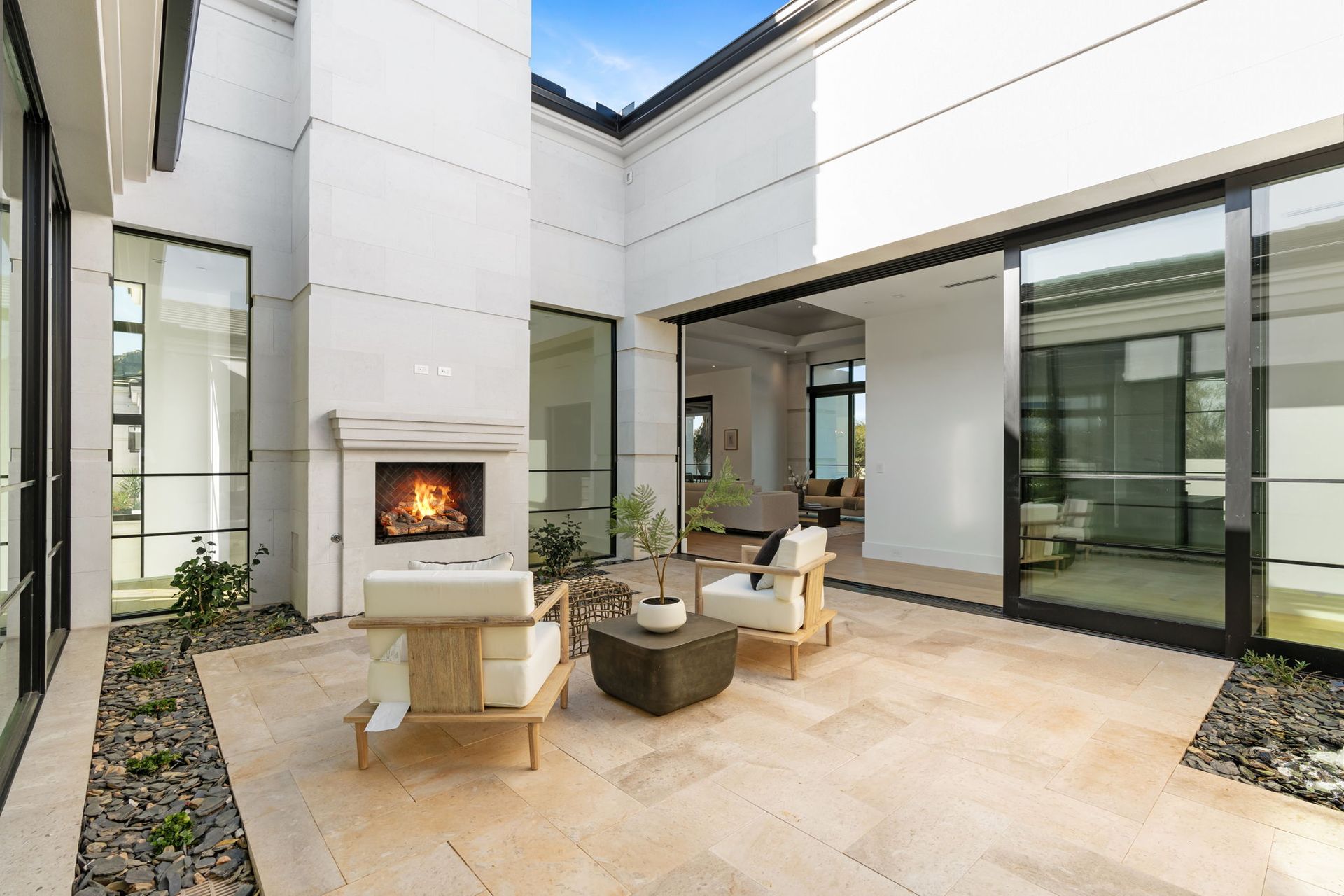 Patio with fireplace, seating, and sliding glass doors. Bright, neutral tones.