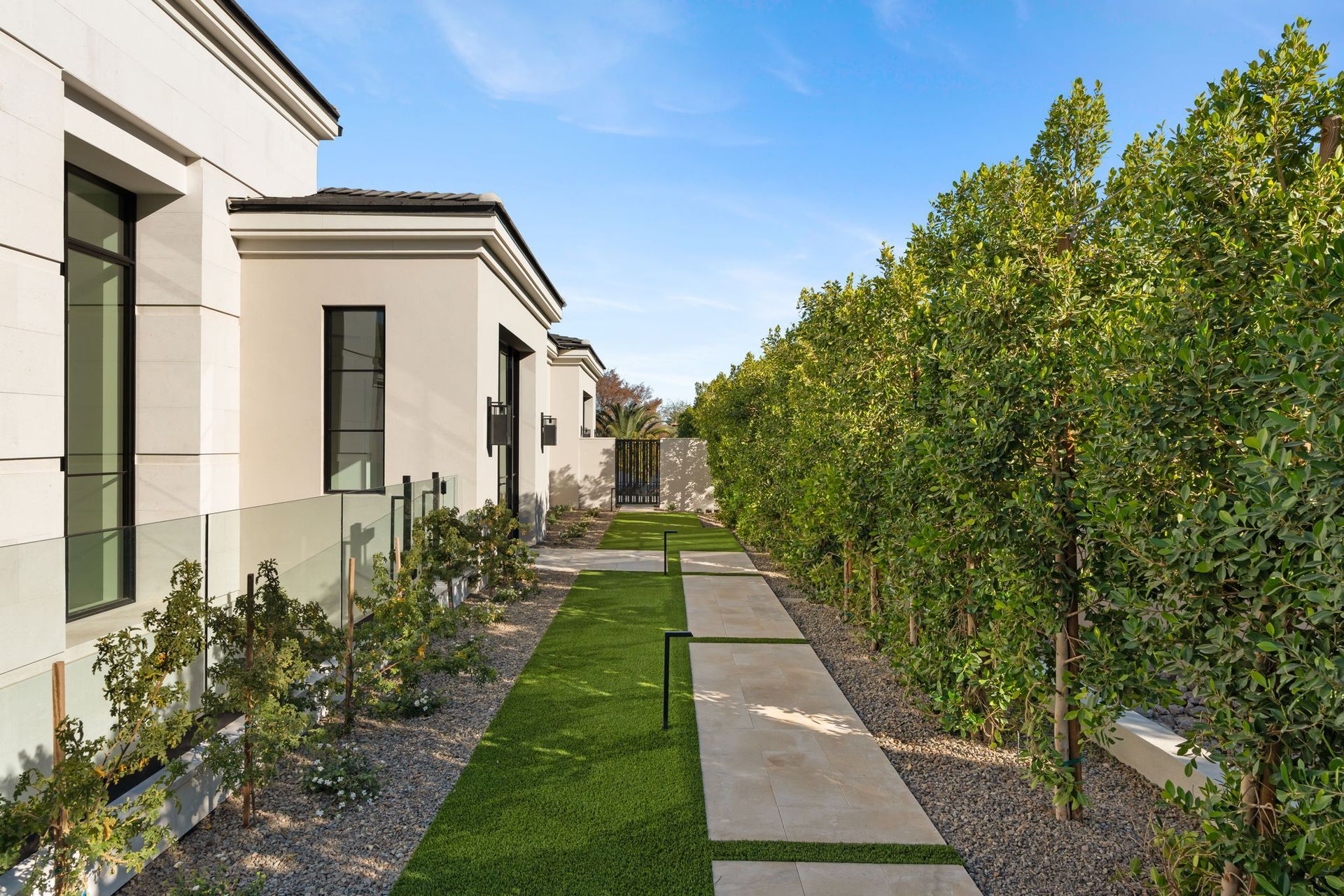 Entry to modern home with green hedges and lawn.