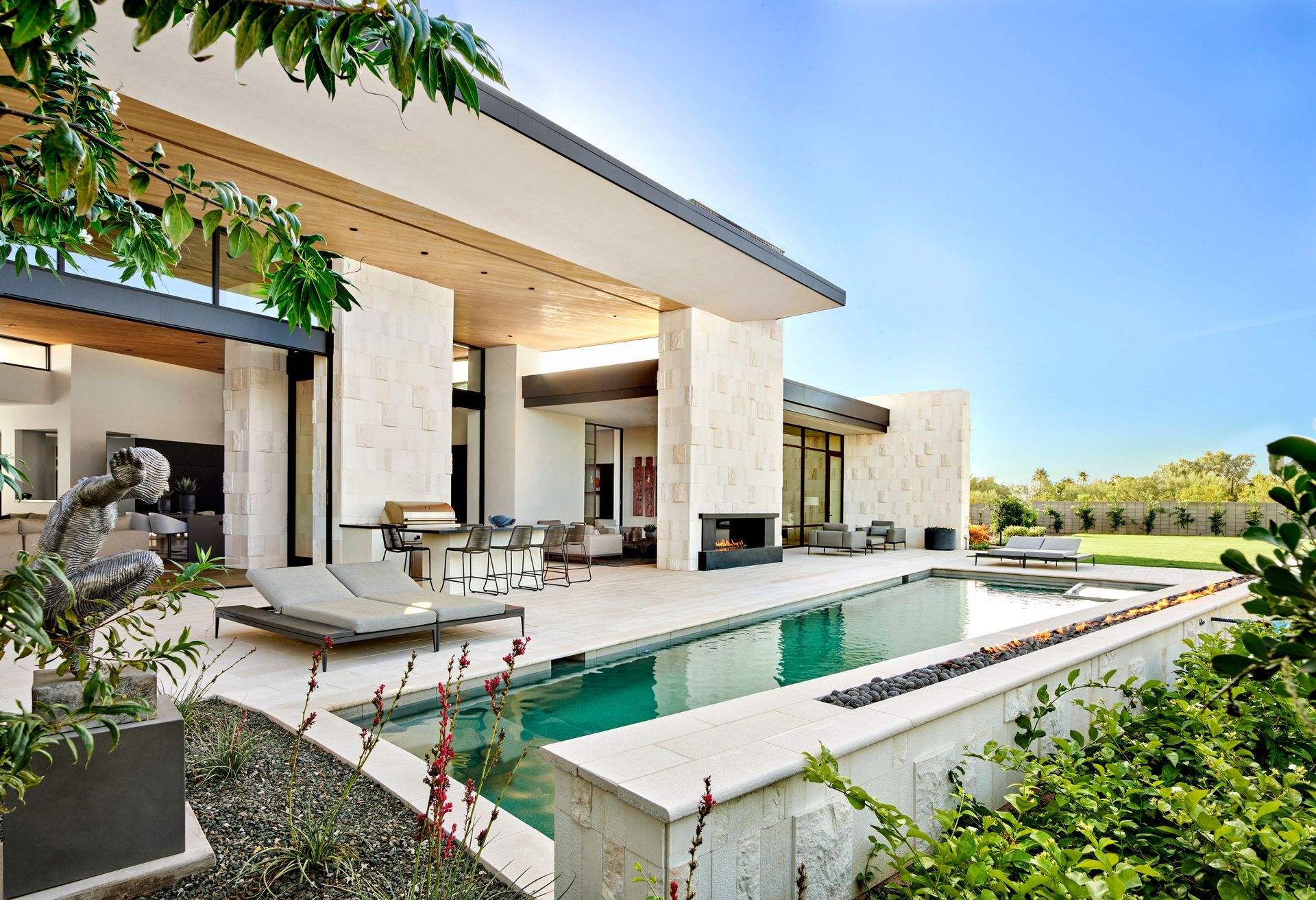 Modern home with pool, patio, and fireplace on a sunny day.