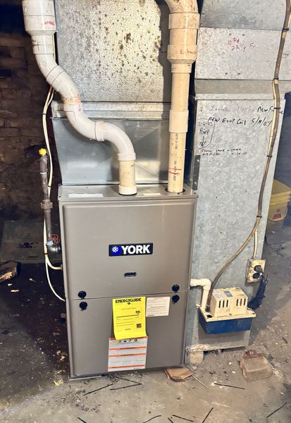 A york furnace is sitting in a basement next to a wall.