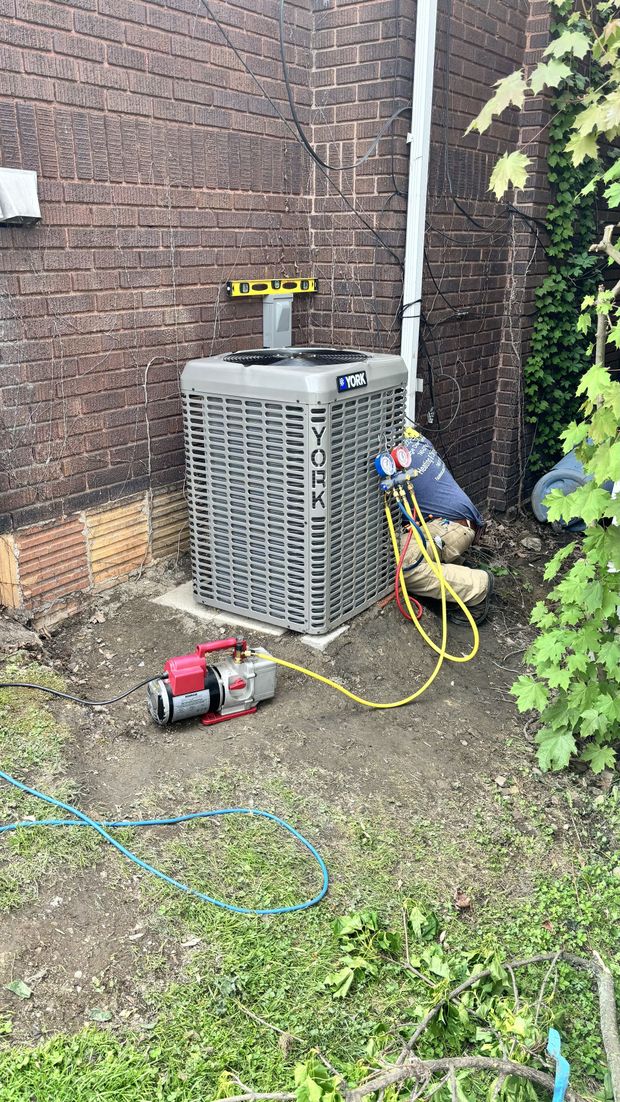 An air conditioner is being installed in the backyard of a house.