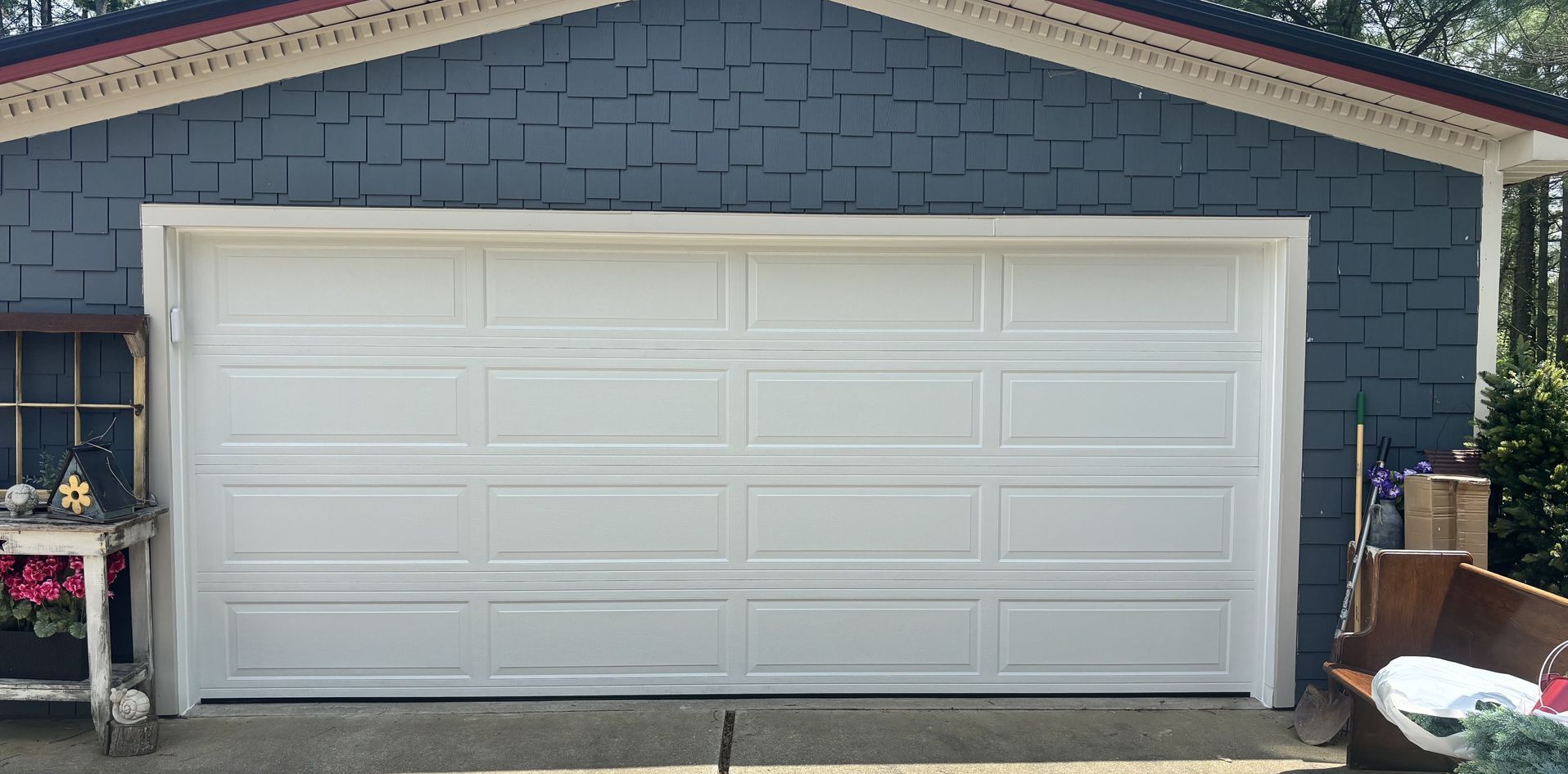 A white garage door is sitting in front of a blue house.