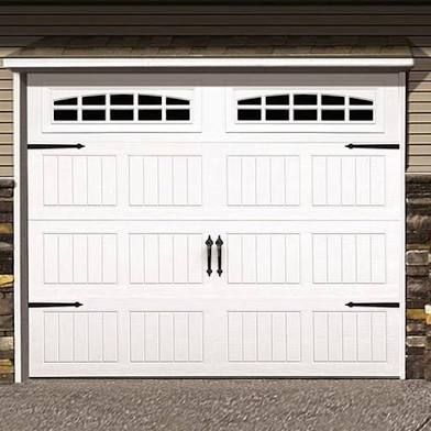 A white garage door with black handles is sitting next to a stone wall.