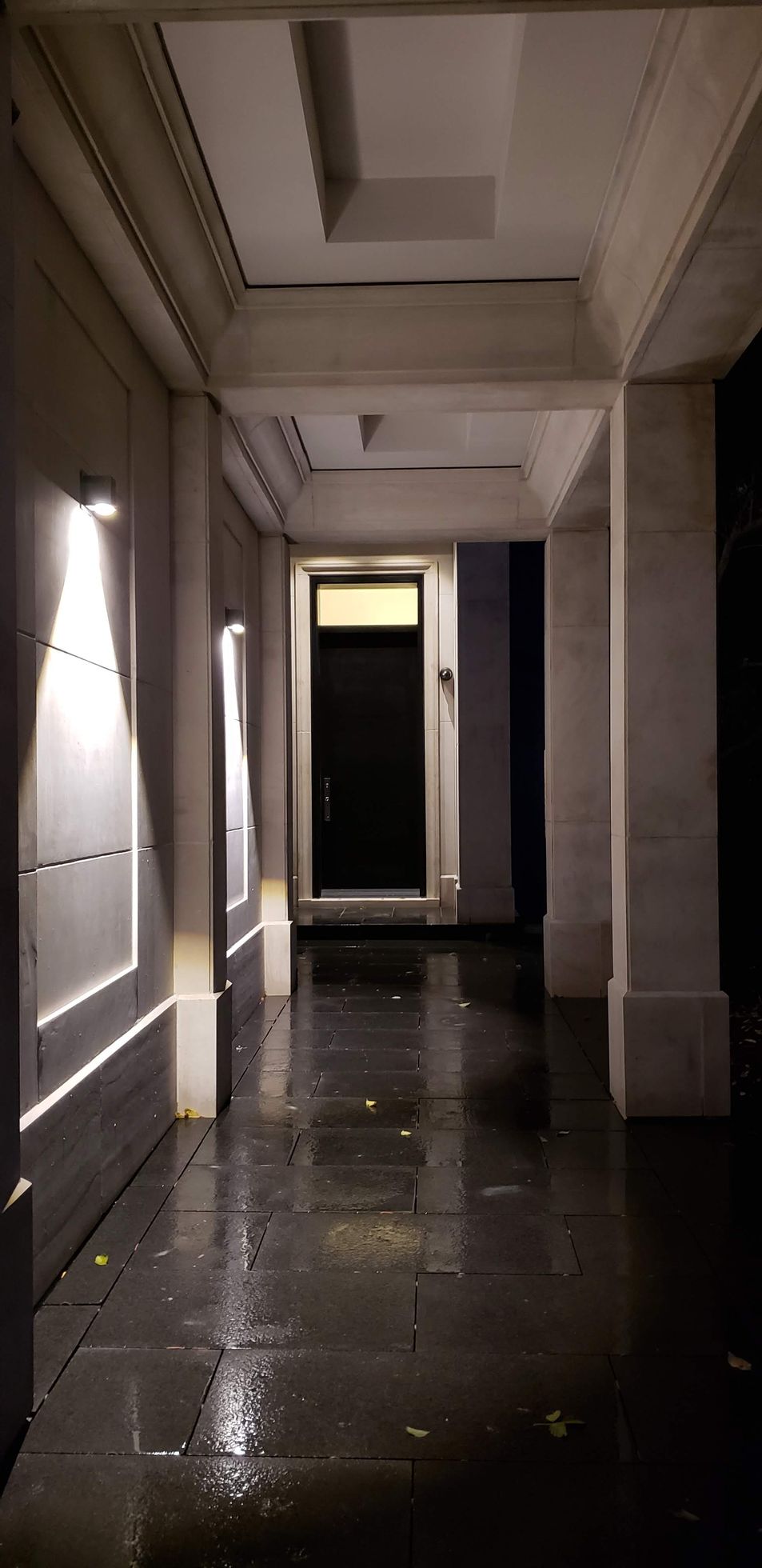 A long hallway with a door in the middle of it at night.