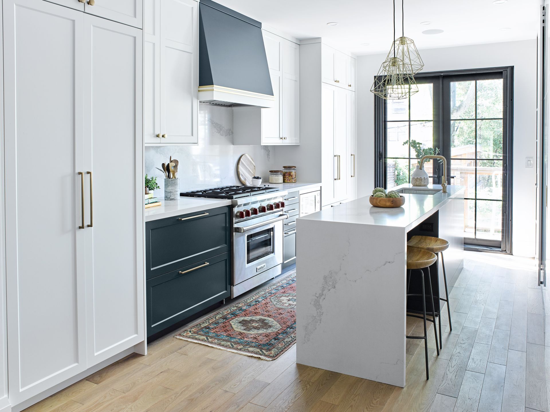 A kitchen with white cabinets , stainless steel appliances , and a large island.