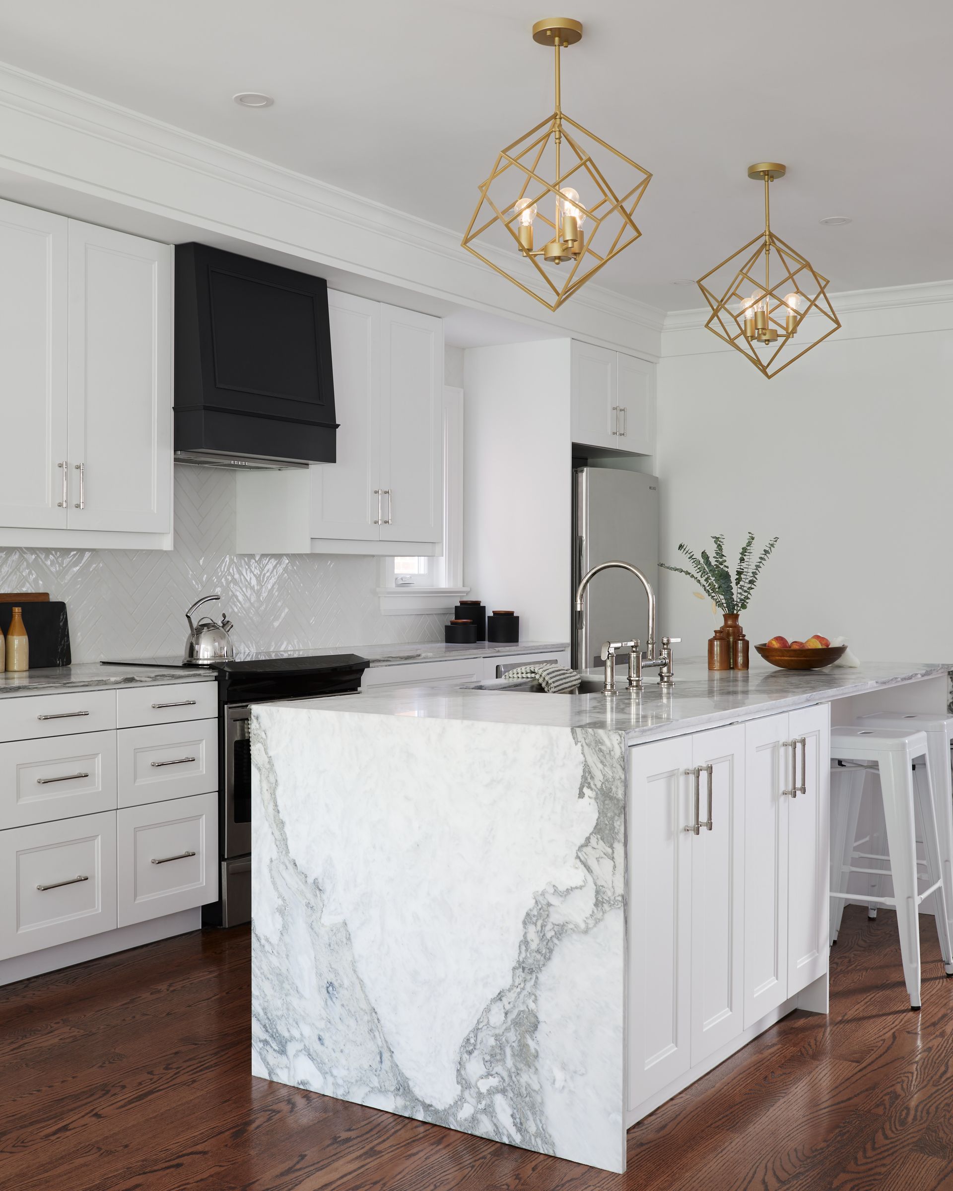 A kitchen with white cabinets and a large marble island.