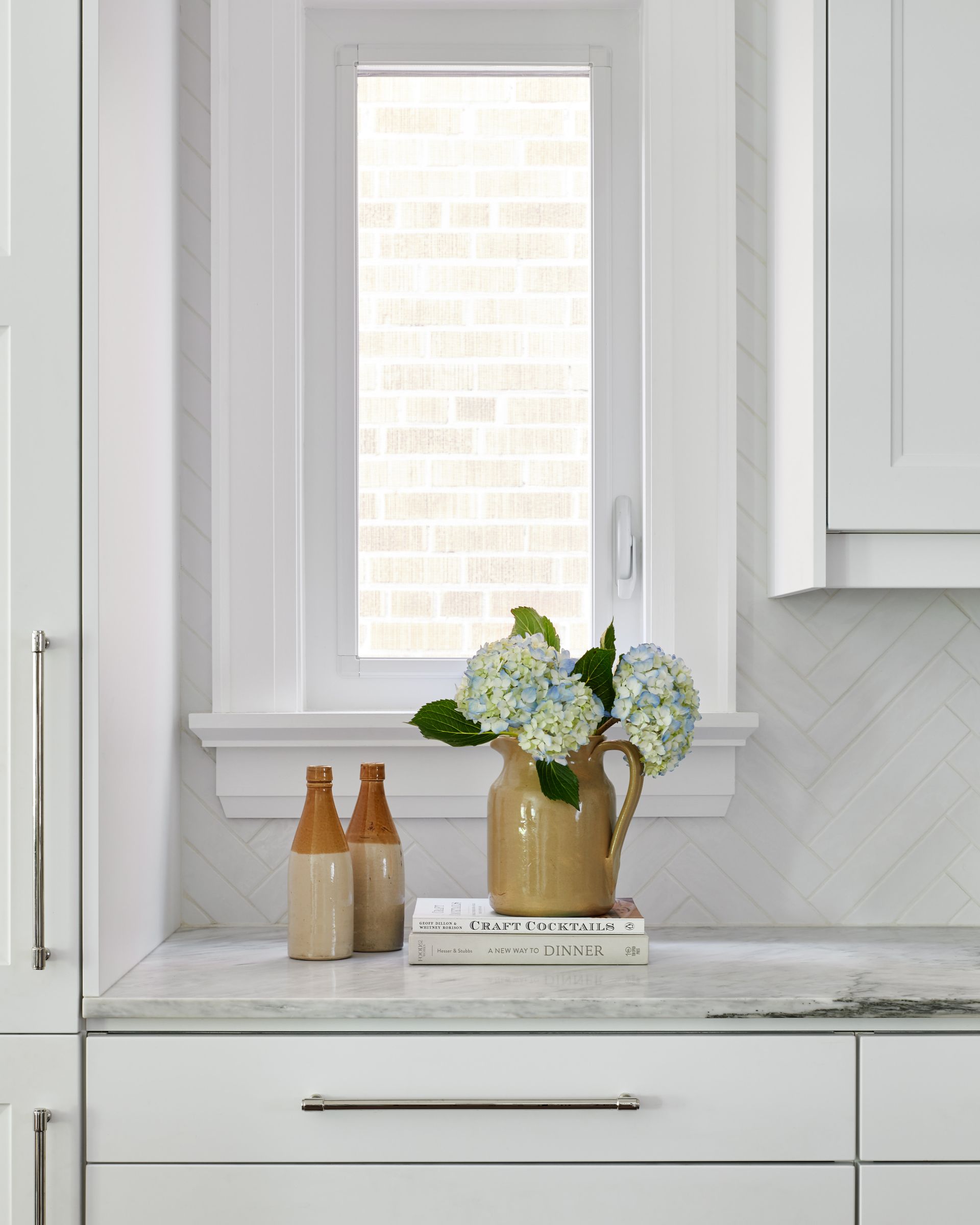 There is a vase of flowers on the counter in the kitchen.