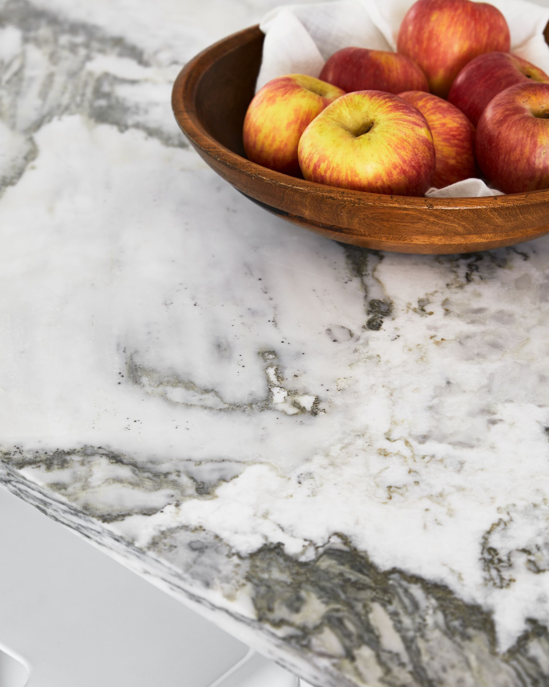 A bowl of apples on a marble counter top