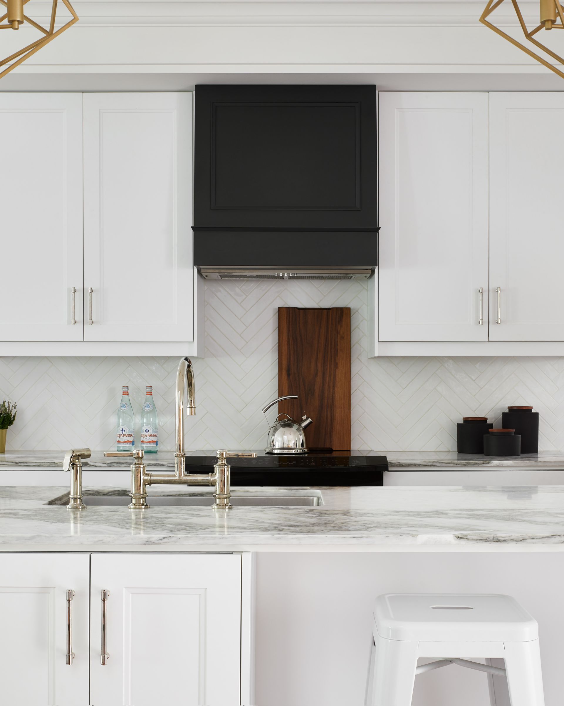 A kitchen with white cabinets and a black hood above the sink.