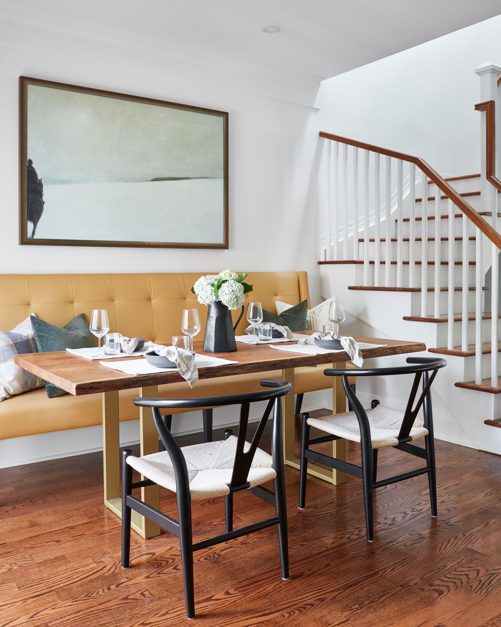 A dining room with a table and chairs and stairs.