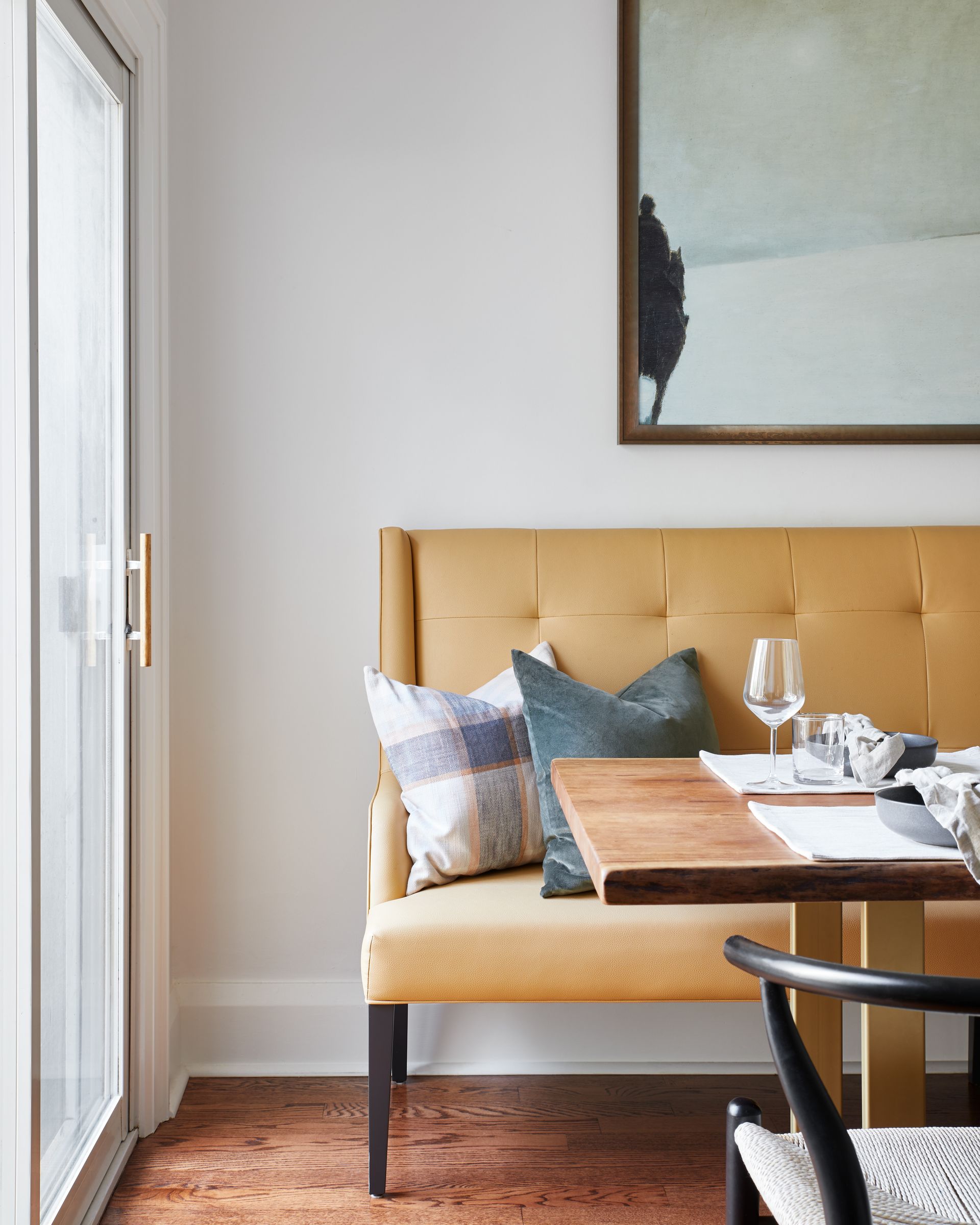 A dining room with a yellow bench and a wooden table