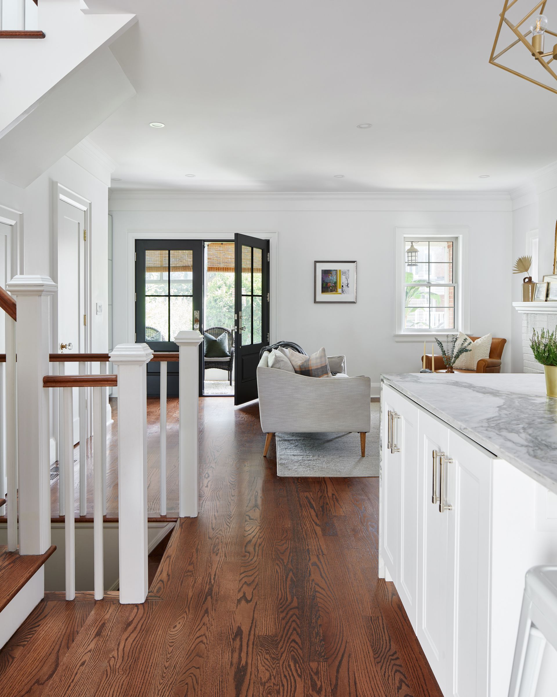 A kitchen and living room with hardwood floors and white cabinets.
