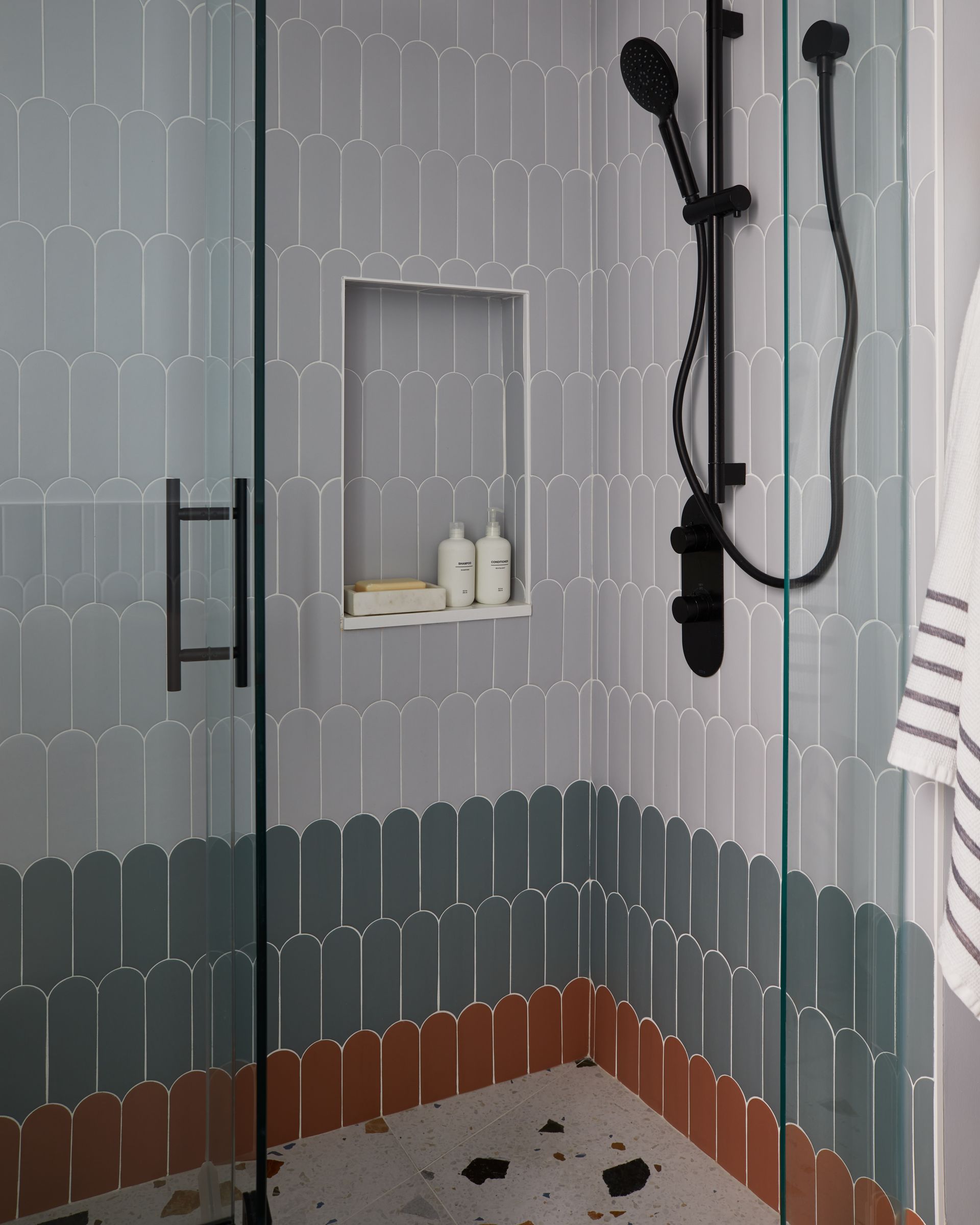 A bathroom with a shower stall and a towel on the floor.
