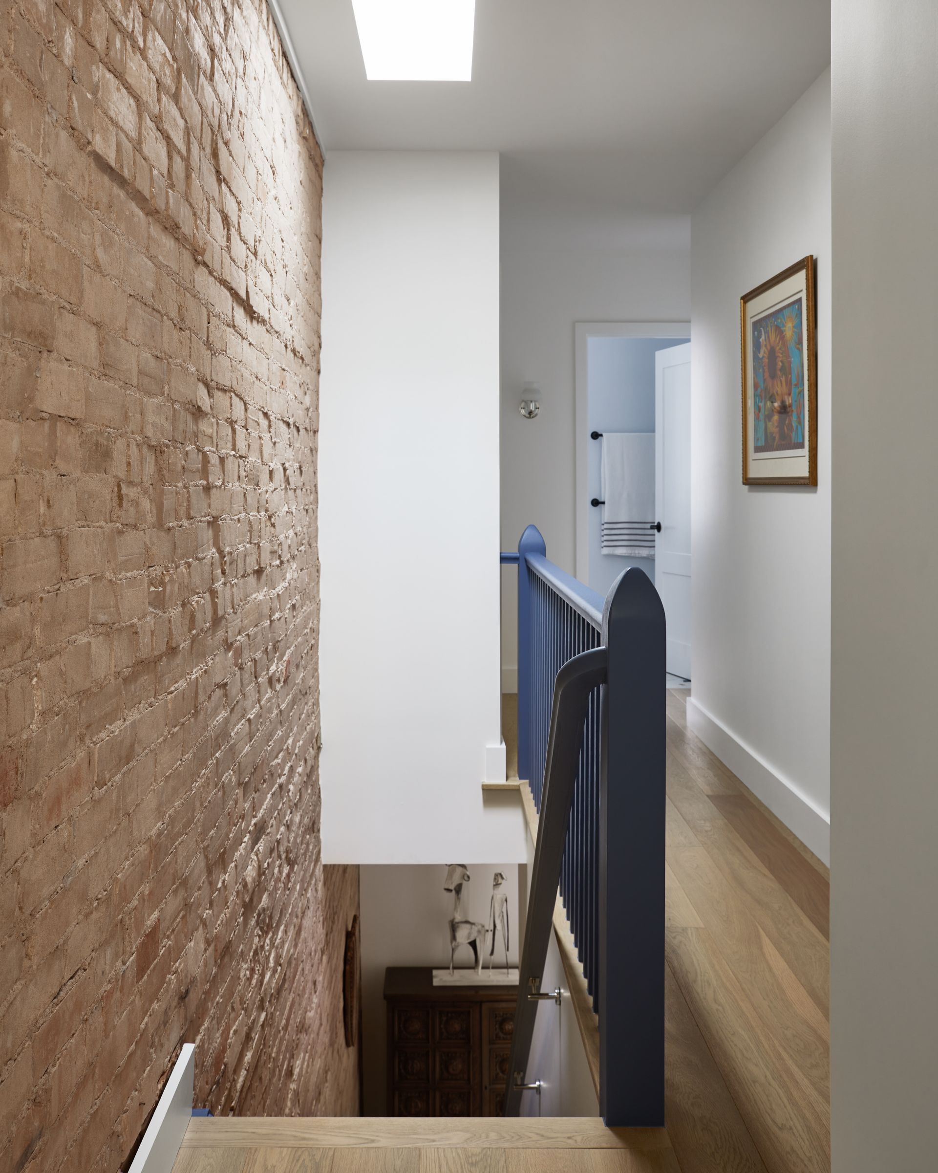 A hallway with a blue railing and a brick wall