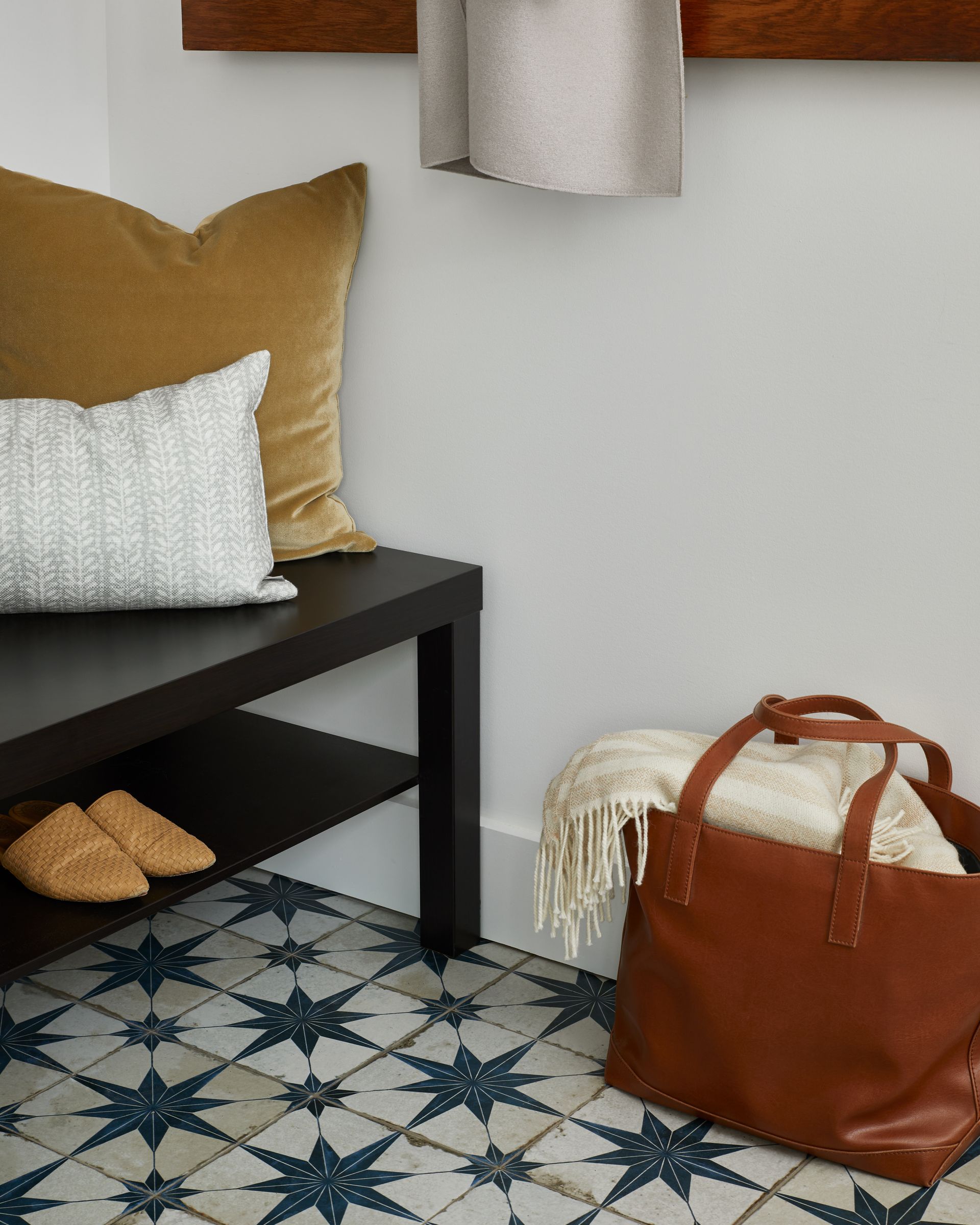 A brown leather bag is sitting on the floor next to a bench.