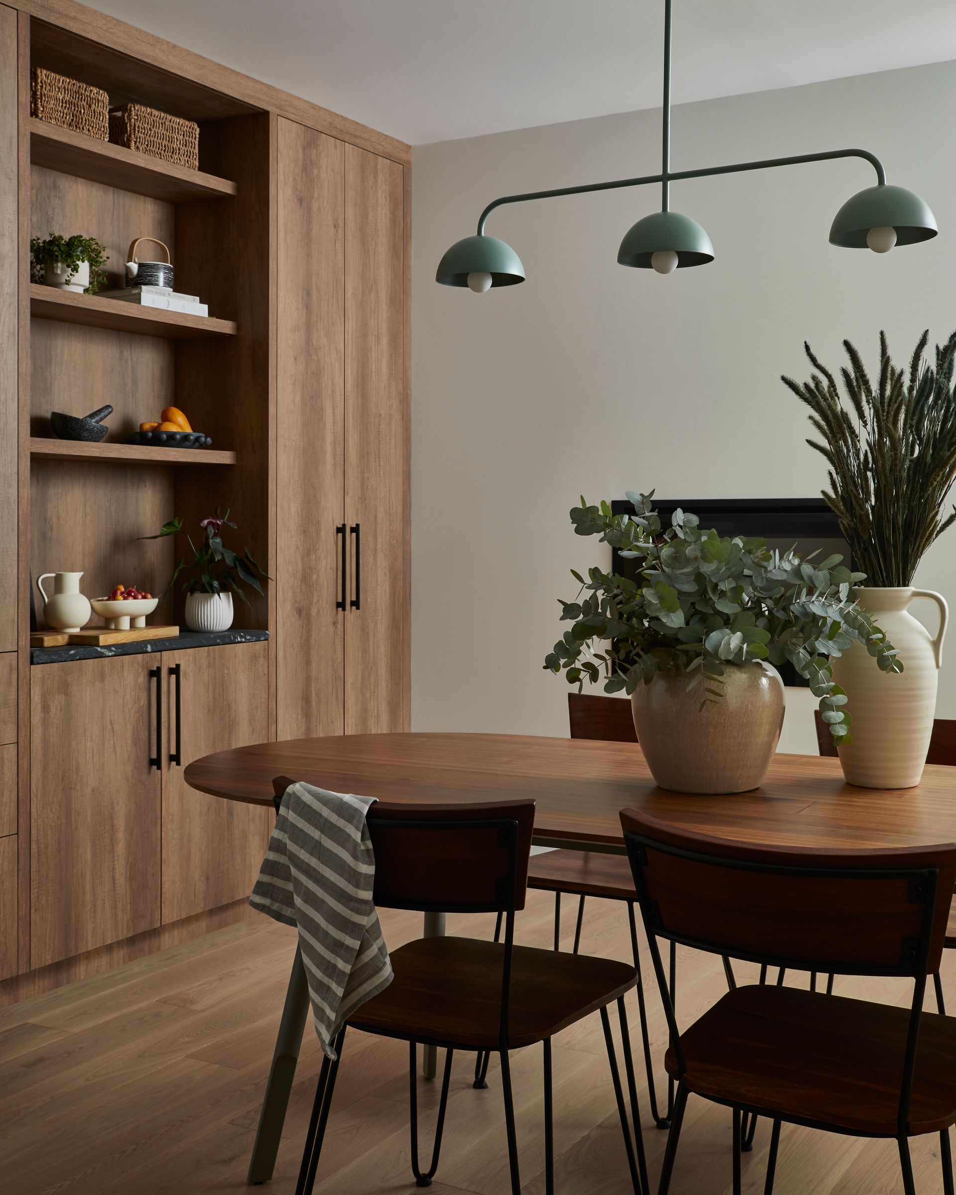 A dining room with a table and chairs and a potted plant on the table