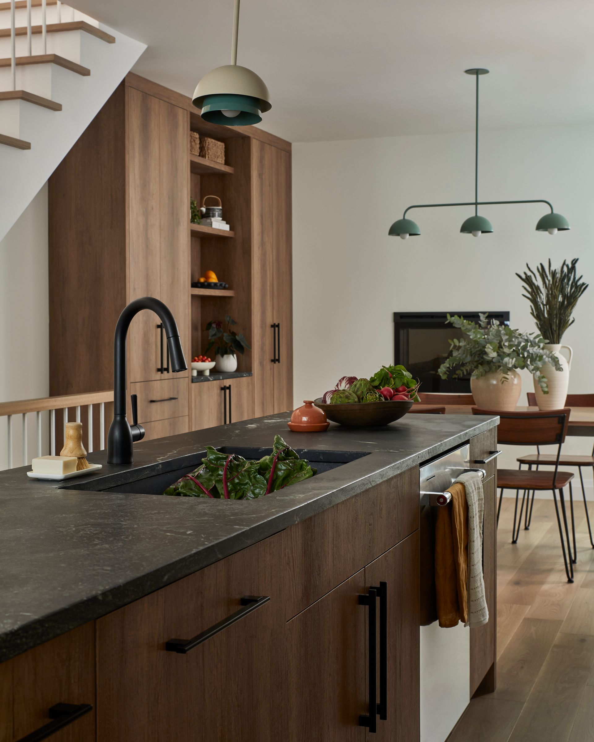 A kitchen with a sink and a staircase in the background