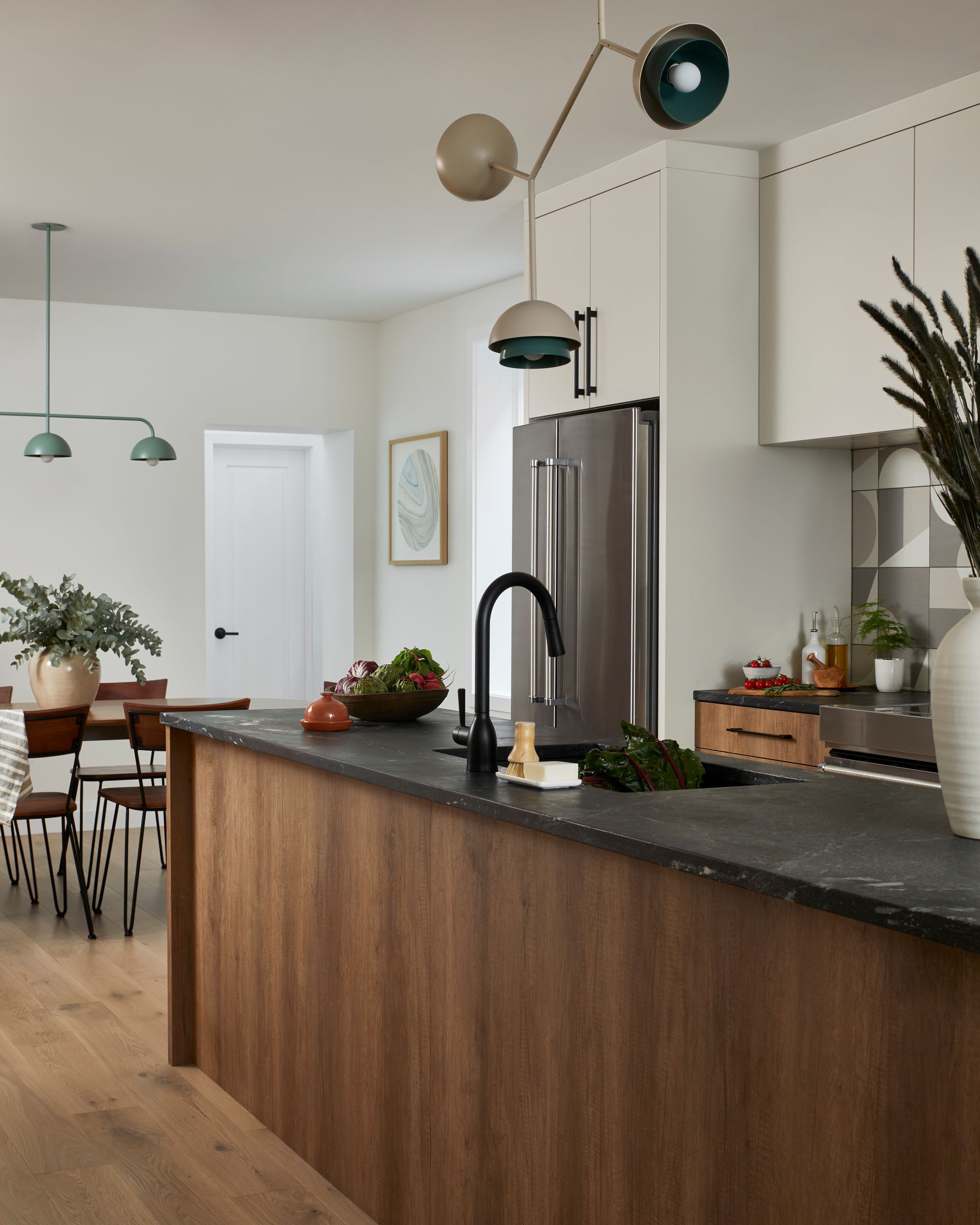A kitchen with a large island and a stainless steel refrigerator