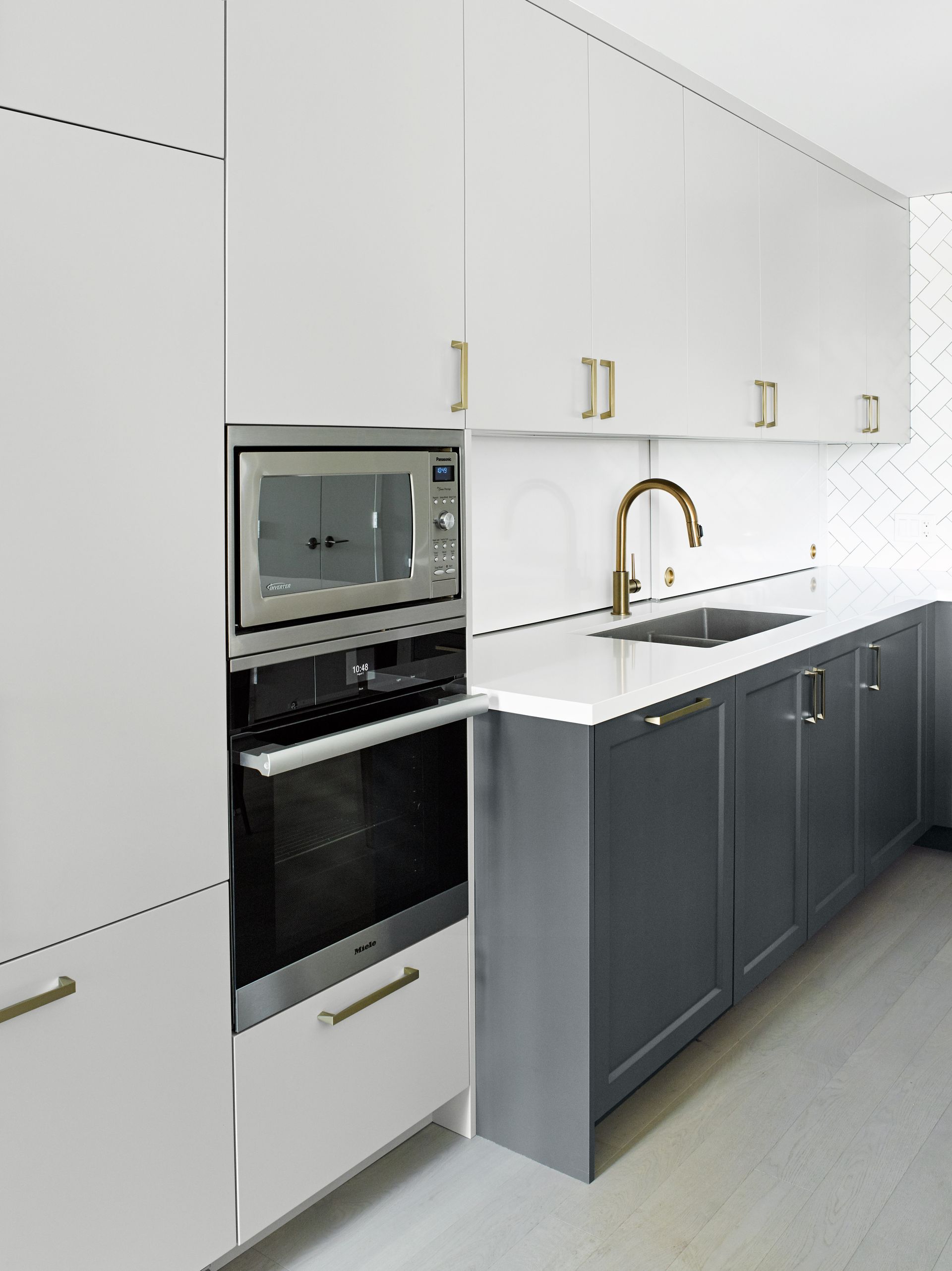 A kitchen with white cabinets and gray counter tops