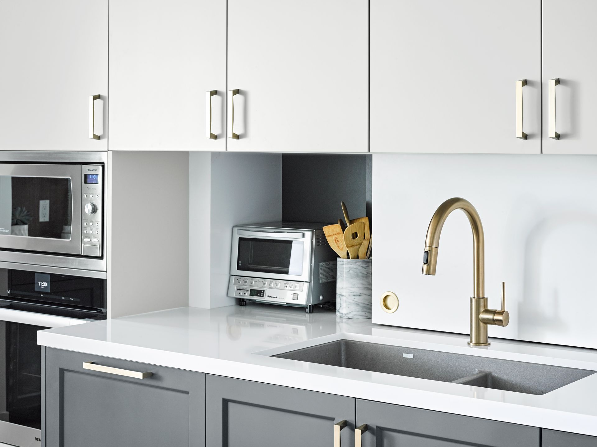 A kitchen with a sink , microwave , and toaster oven.