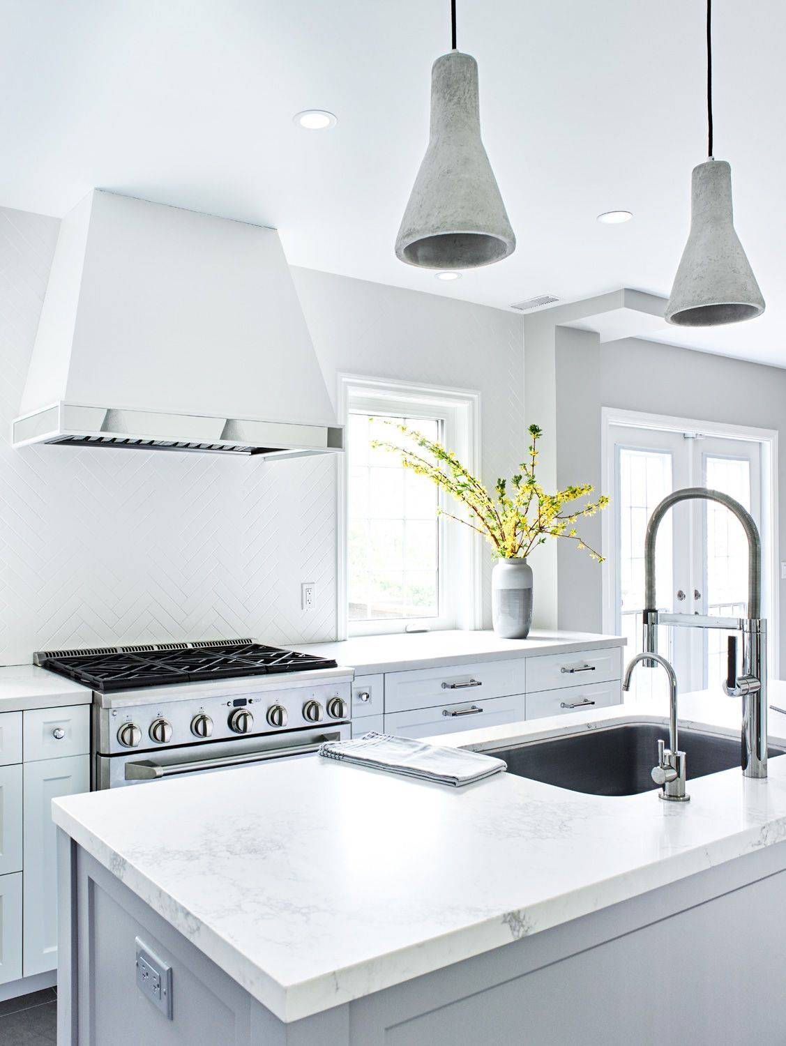 A kitchen with a sink , stove , and hood.