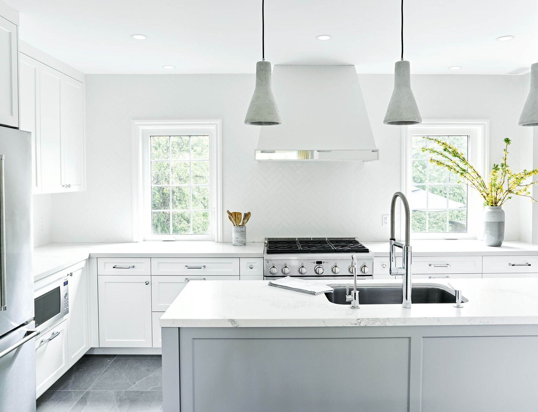 A kitchen with white cabinets , stainless steel appliances , a sink and a stove.