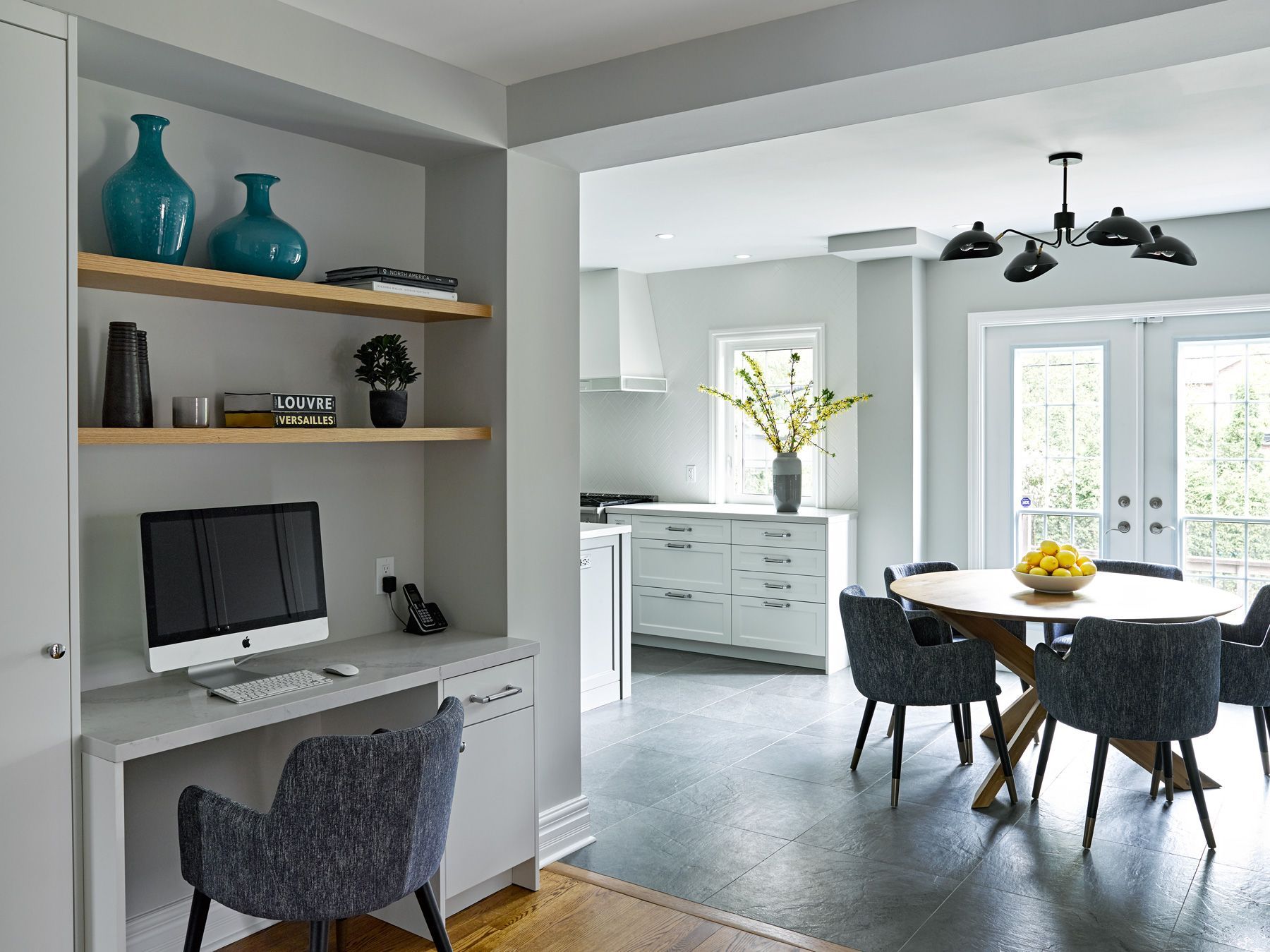 A dining room with a table and chairs and a desk with a computer on it.