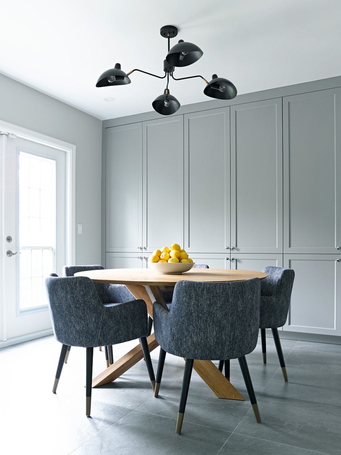 A dining room with a table and chairs and a bowl of lemons.