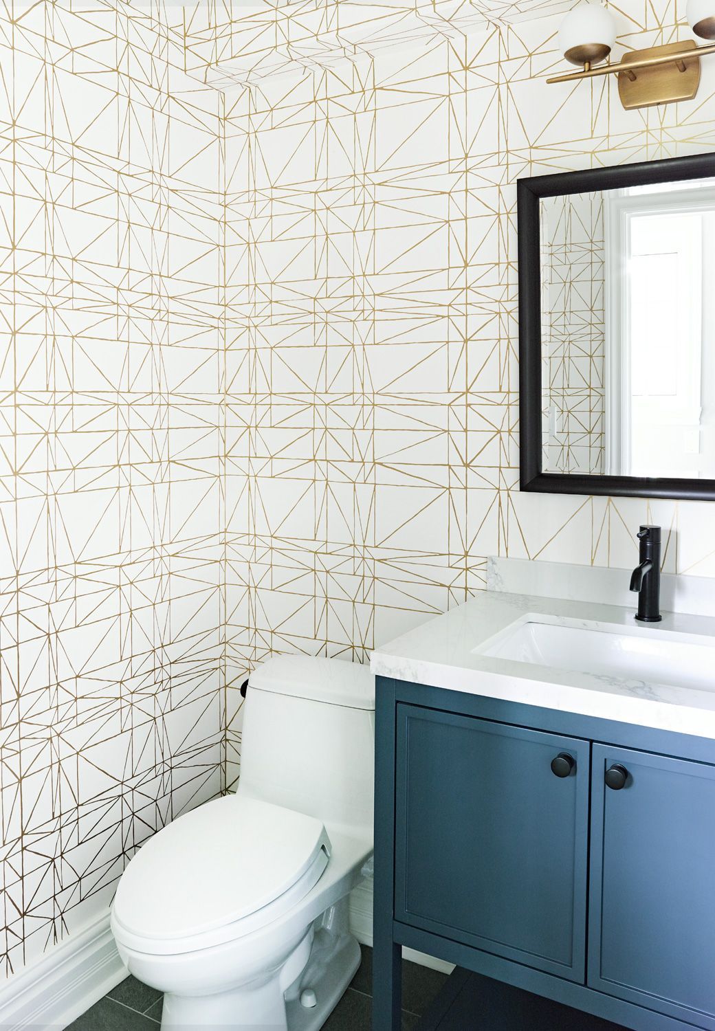A bathroom with a toilet , sink and mirror.