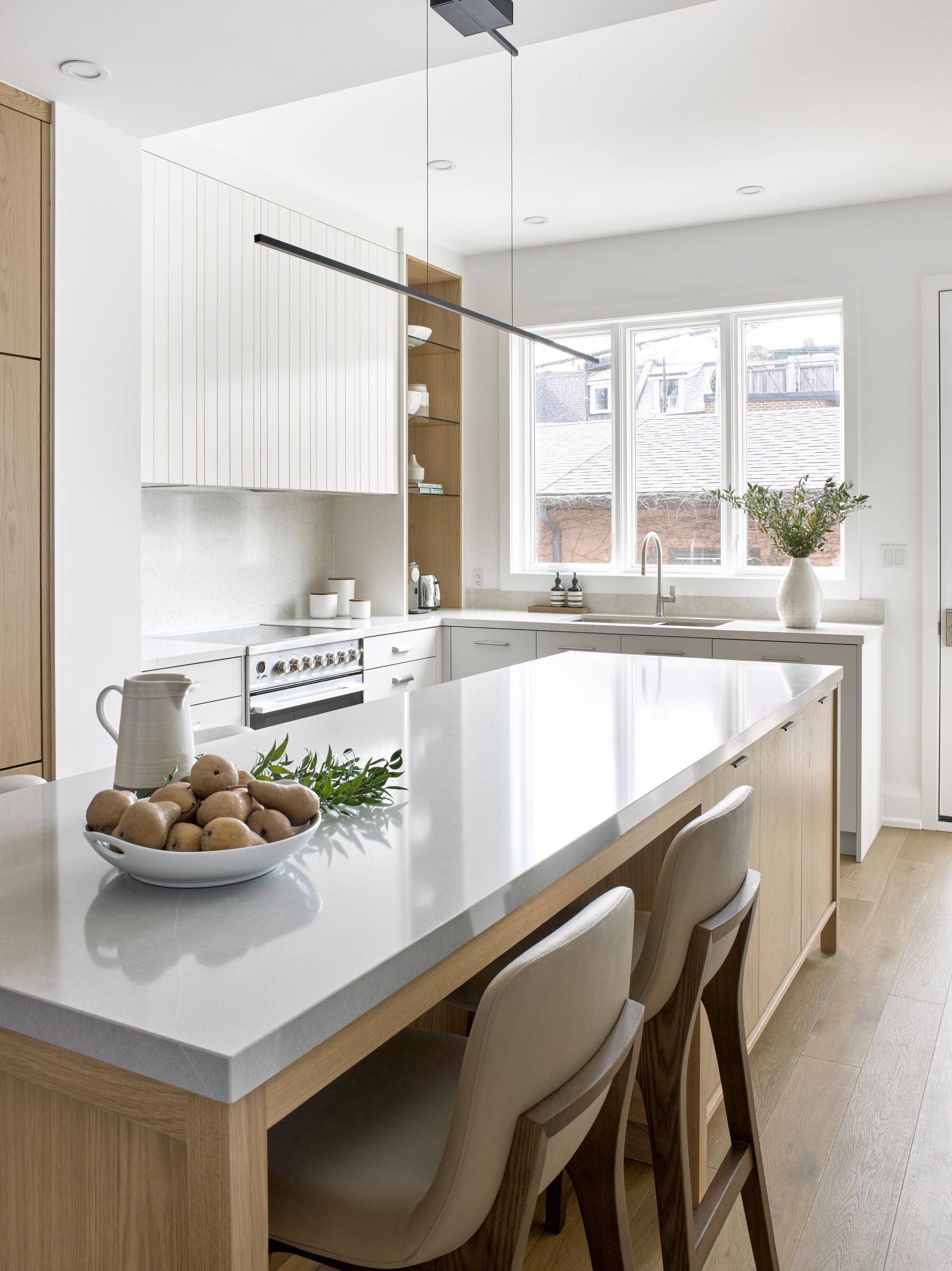 A kitchen with a large island and a bowl of potatoes on the counter.