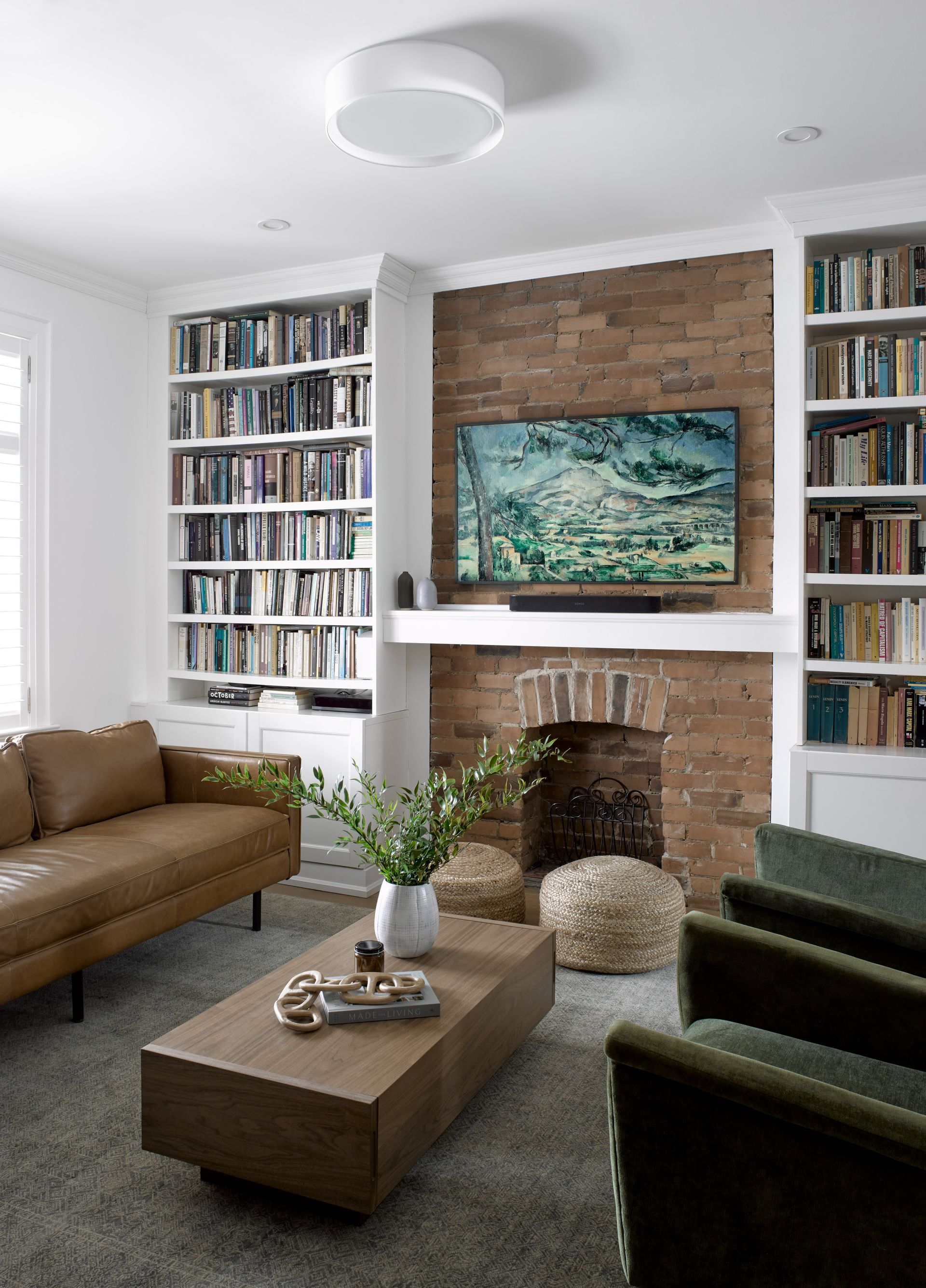 A living room with a couch , chairs , coffee table , fireplace and television.